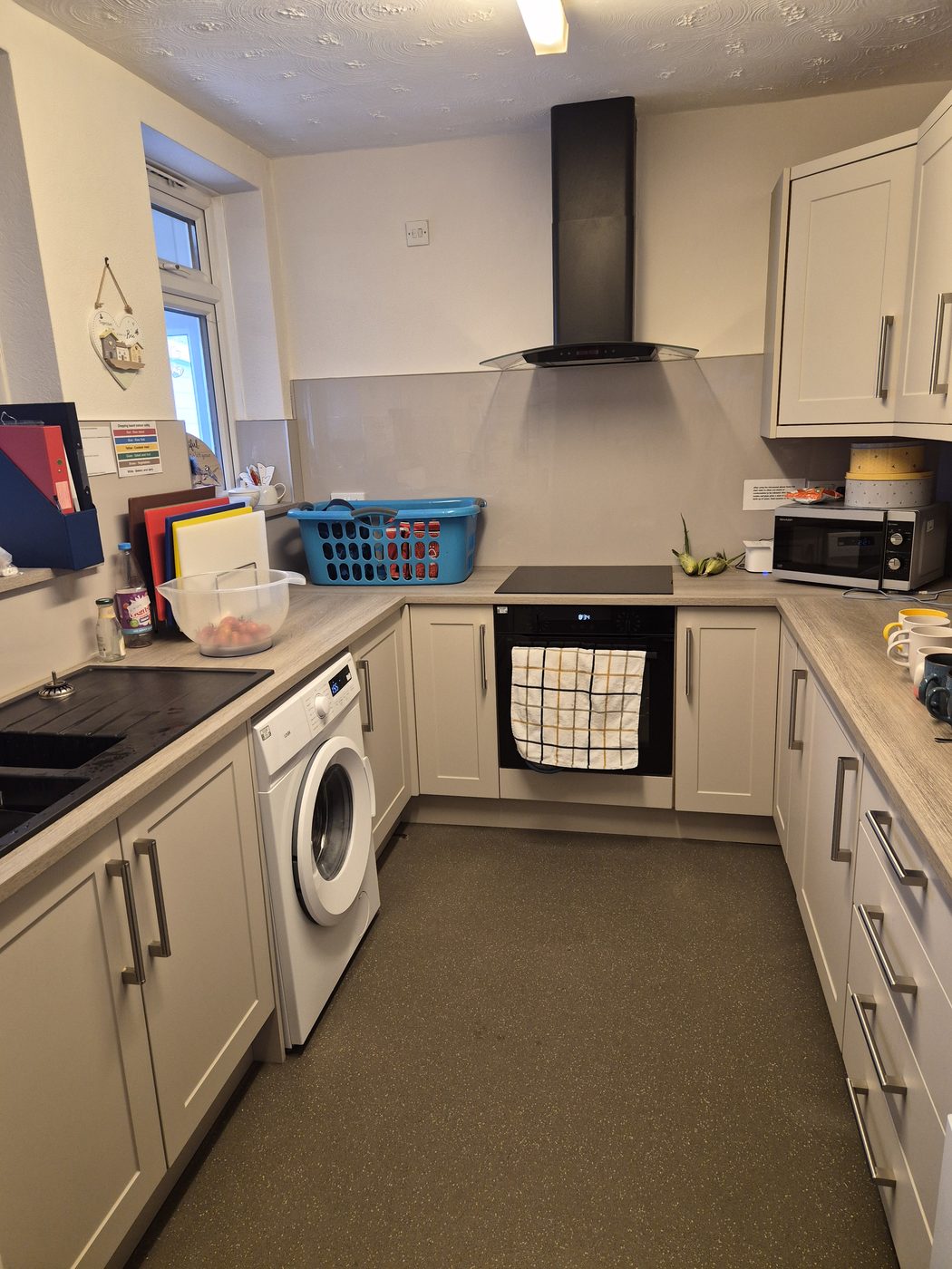 A clean, modern kitchen with cream units, a hob, oven and colour-coded chopping boards.